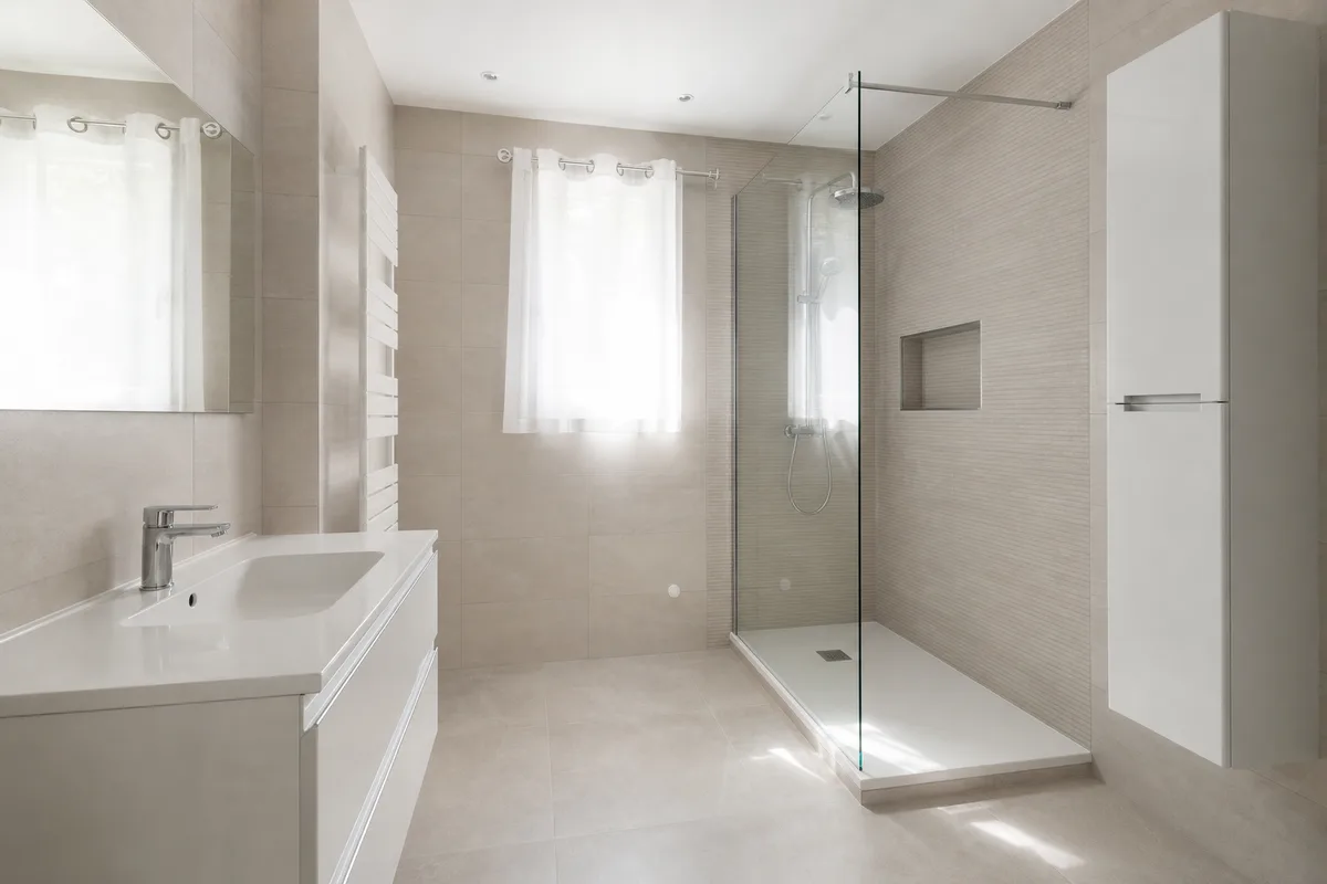 Salle de bain rénovée avec faïence claire et receveur de douche extra-plat